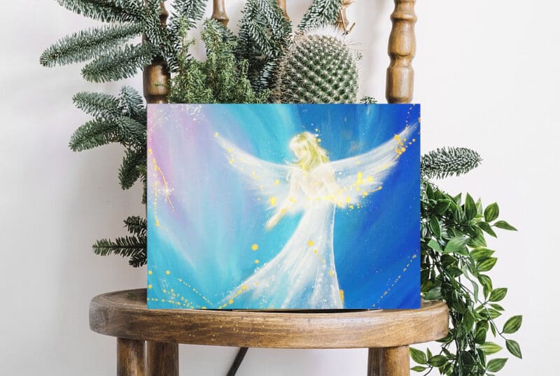 Engelbild in Blau mit goldenen Sprenkeln auf einem Stuhl